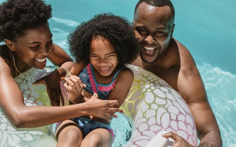 a man and woman holding a child in a pool