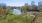 a pond surrounded by grass and trees and a dog park