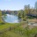 a pond surrounded by grass and trees and a dog park