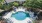 a swimming pool with chairs and umbrellas in a backyard