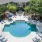 a swimming pool with chairs and umbrellas in a backyard