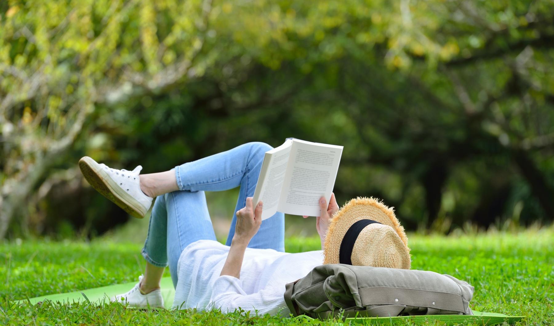 Settle into comfort at Saw Mill Village a person lying on the grass reading a book